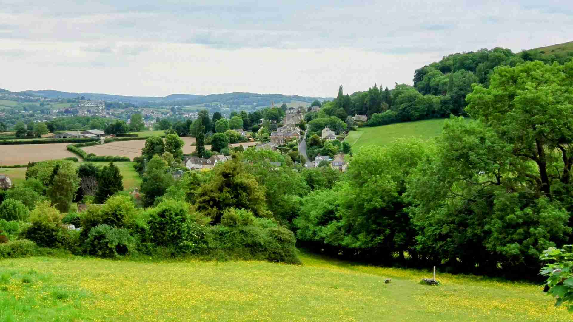 View over Selsley in Gloucestershire, showing open grasslands, rolling green hills and Selsley church in the distance
